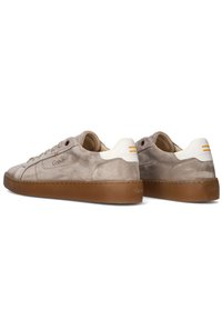 Beige Wildlederschuhe mit weißen und orangen Akzenten, runder Schuhspitze, flacher Gummisohle und genähten Details an den Seiten.