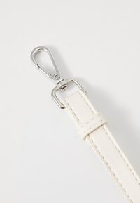 Vit läderrem med sömmar, utrustad med en silverfärgad metallkarbin för säker fästande. Slät textur och minimalistisk design.
