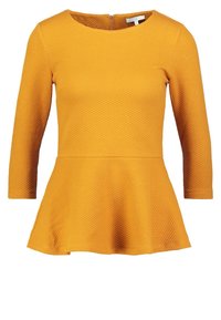 Geel peplumtop met lange mouwen, textuurstof, ronde halslijn en een rits aan de achterkant. Heeft een uitlopende zoom en een getailleerd lijfje.