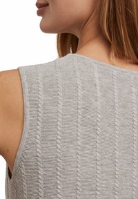 Szary dzianinowy top z pionowymi prążkami i wzorem warkoczowym. Bez rękawów, z okrągłym dekoltem.