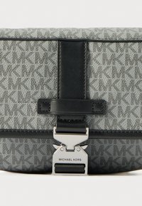 Gray monogrammed fabric clutch with a black leather strap, silver hardware clasp, and embossed logo. Features a structured, rectangular design.