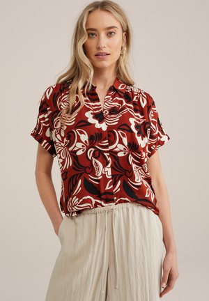 Rode short-sleeve shirt met een gedurfde zwart-witte bloemenprint, met een gekraagde halslijn en een knoopsluiting aan de voorkant.