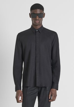 Schwarzes Langarmhemd aus einem glatten, leichten Stoff mit Button-down-Kragen, geradem Saum und minimalistischem Design.