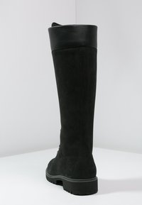 Höga svarta mockastövlar med matt finish, som har en bred svart lädermanschett och en slitstark gummisula. Inga synliga detaljer eller mönster.