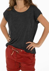 Mörkgrå kortärmad topp med rund hals, kombinerad med röda shorts med ett mönstrat bälte och uppvikta ärmar, som visar en avslappnad passform.