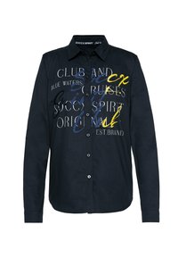 Camicia blu navy in cotone con colletto a punta, caratterizzata da audaci scritte bianche, gialle e blu sulla parte frontale.