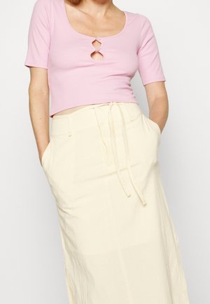 Roze geribbelde crop top met korte mouwen, met een sleutelgatdetail, gecombineerd met een crèmekleurige midi-rok met een trekkoord in de taille en zijzakken.
