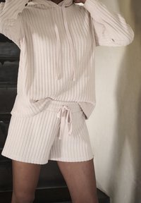 Beżowa, prążkowana bluzka z kapturem z długimi rękawami i sznurkiem, w zestawie z dopasowanymi prążkowanymi szortami z elastycznym pasem i luźnym krojem.