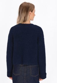 Maglione lavorato a maglia blu navy con tessuto testurizzato, lunghezza cropped, maniche larghe e scollo rotondo, con accenti a coste.