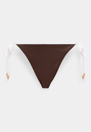 Rjave spodnjice bikinija z belimi stranskimi trakovi in zlatimi perlicami, položene na svetlo podlago.