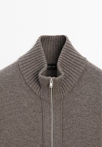 Grauer Strickpullover mit hohem geripptem Kragen, Reißverschluss und weicher Textur. Etikett sichtbar im Krageninneren: Massimo Dutti.