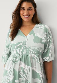 Bloemenjurk in lichtgroen en wit, met een V-hals, korte pofmouwtjes en een geplooide taille voor een losse pasvorm.