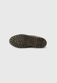 Botte en cuir marron avec une semelle en caoutchouc robuste dotée de profondeurs de profil et du logo Timberland, conçue pour la durabilité et l'adhérence.