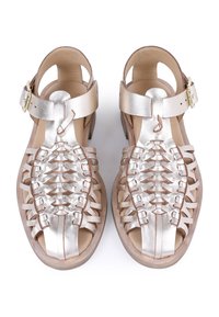 Sandalias de cuero metálico plateado con un diseño trenzado, puntera abierta, tira en el tobillo y tacón de madera. Presentan una textura suave y acentos mínimos.