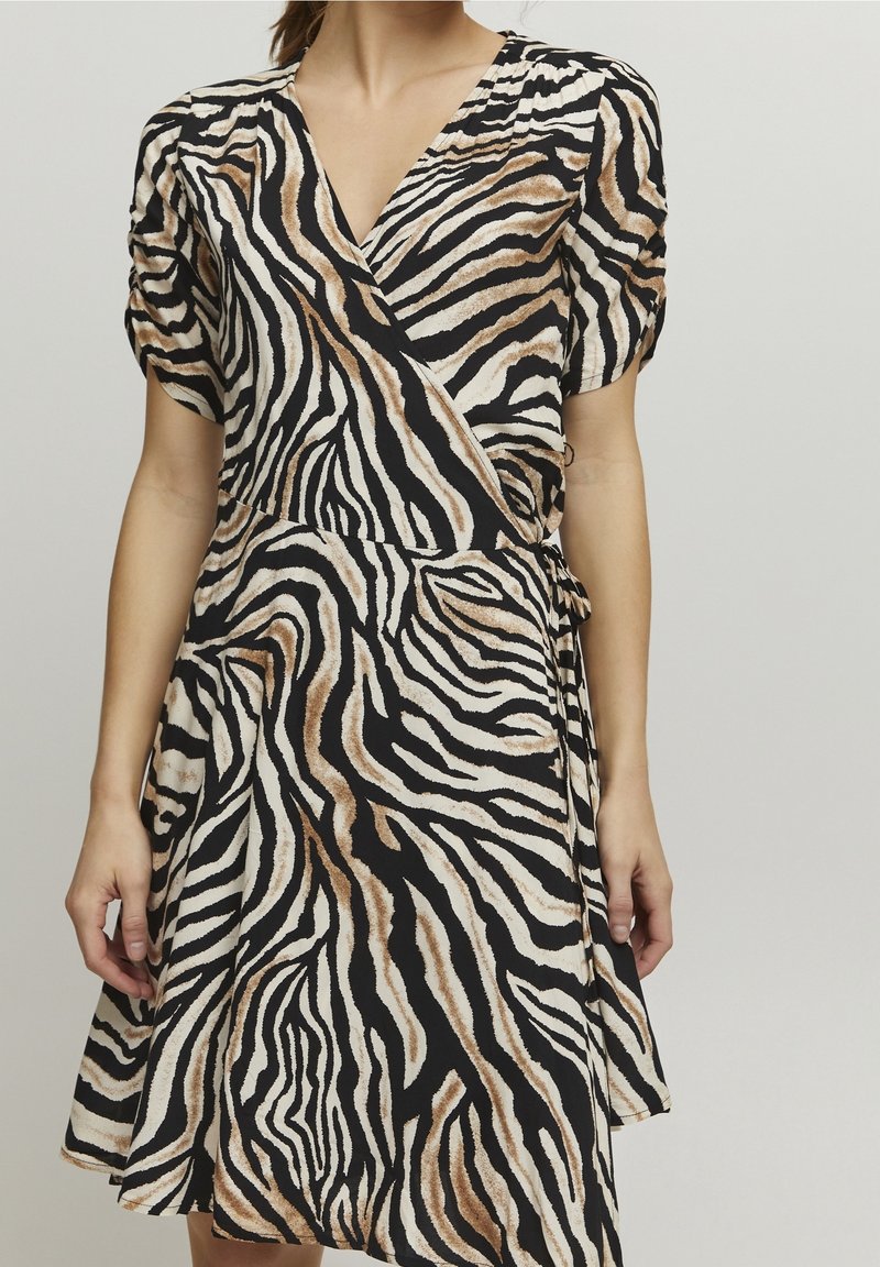 Zebrajousu, joka on musta, valkoinen ja tanvärinen; siinä on pullistuvat lyhyet hihat ja säädettävä vyötärösolki.