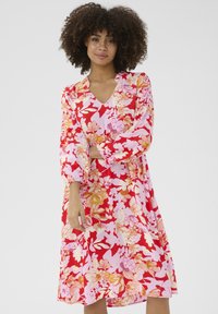 Lillelille kleit V-kaelusega, mis on kaunistatud suurte roosa ja punase lilledega roosa tausta peal. Pikad varrukad kogutud mansettidega. Sile kangas.