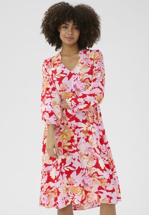 Blumenkleid mit V-Ausschnitt, versehen mit großen rosa und roten Blumen auf einem rosa Hintergrund. Lange Ärmel mit gerafften Bündchen. Glatter Stoff.