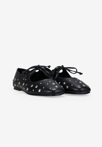 Zapatillas de ballet negras de cuero con tachuelas plateadas y lazos delanteros, exhibidas lado a lado sobre un fondo blanco.