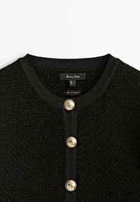 Cardigan en maille texturée noire avec encolure ronde et trois boutons décoratifs dorés sur le devant, étiquette Massimo Dutti, fabriqué en Turquie.