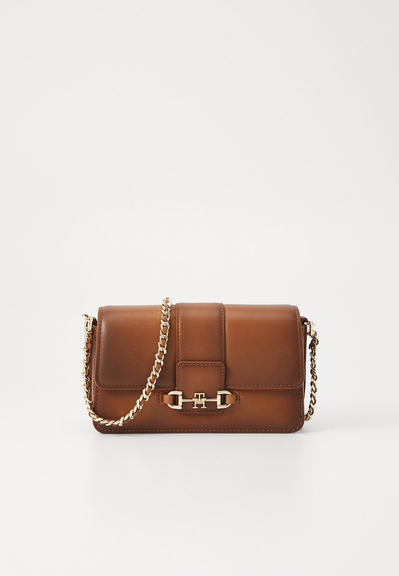 Ruda odinė petneša su grandinės diržu, stačiakampio formos, su užklotu uždarymu ir auksinėmis detalėmis priekyje. Minimalistinis dizainas.