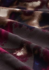 Abstract fabric featuring shades of dark purple, burgundy, and brown with a smooth texture and subtle gradient patterns throughout.