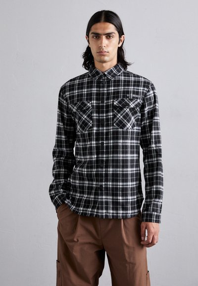 Zwart-wit geblokte button-up shirt met twee borstzakken, lange mouwen en een klassieke kraag. Gemaakt van een zachte stof met een geruite print.
