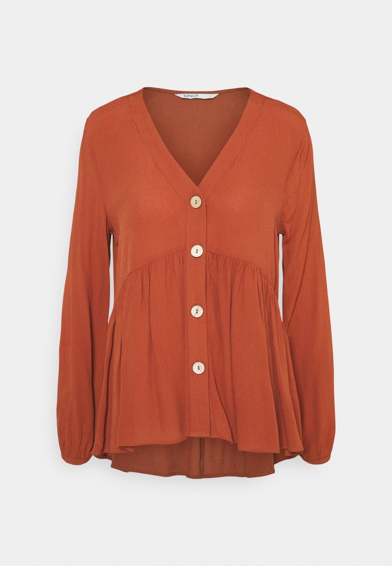 Blouse couleur rouille avec des manches longues, décolleté en V et cinq boutons en bois sur le devant. Présente une taille plissée pour plus de texture.