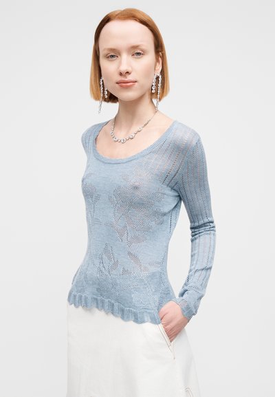 Pull en tricot bleu clair à manches longues, avec un motif floral et un ourlet côtelé. Le tissu a une texture translucide.