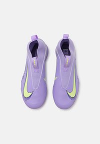 Fialové sportovní boty se skládací konstrukcí, s velkým zeleným logem Nike, texturovaným svrškem a poutky pro snadné obouvání.