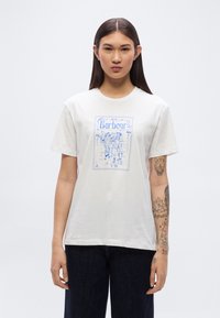 Λευκό φανελάκι με μπλε γραφικό τύπωμα που περιλαμβάνει τη λέξη "Barbour" και εικονογραφήσεις. Κοντά μανίκια, στρογγυλή λαιμόκοψη, βαμβακερό υλικό.