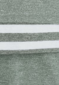 Grauer Baumwollstoff mit strukturierter Oberfläche, der einen weißen horizontalen Streifen aufweist. Weiches, lässiges Erscheinungsbild ohne auffällige Muster oder Hardware.