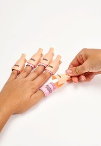 Des protecteurs de doigt en silicone d'une teinte rose clair, conçus pour s'adapter sur les doigts, avec une bande rose portant la mention "informations sur le fabricant".