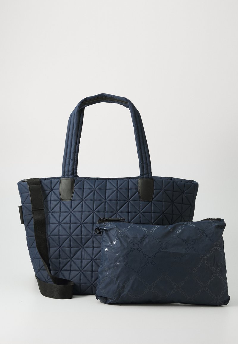 Tumed tikandidega laevastu kvetica, kahe käepideme ja eemaldatava tõmbluku kotiga, millel on peen logo muster.