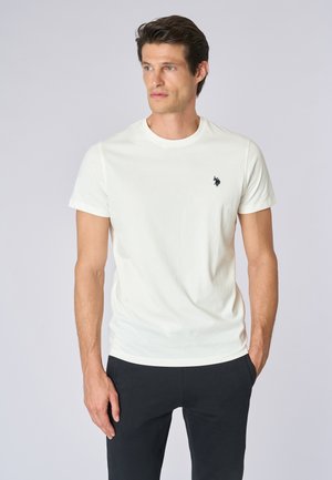T-shirt bianco in cotone con scollo rotondo e maniche corte, caratterizzato da un piccolo logo nero sul lato sinistro del petto. Texture liscia.