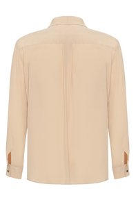 Chemise beige à manches longues avec poignets boutonnés et un pli central dans le dos, vue de dos sur fond blanc.
