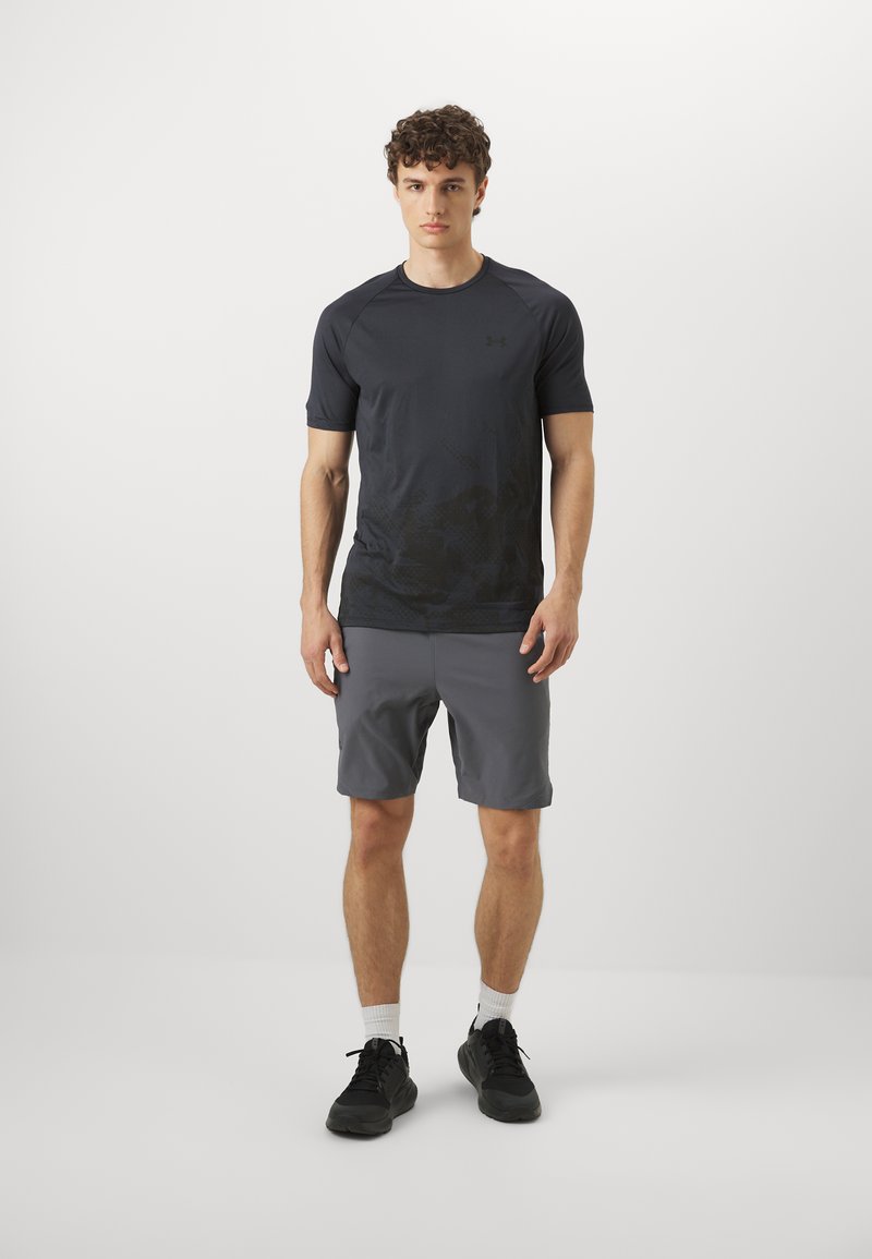 Camiseta atlética de color gris oscuro con mangas cortas, textura estampada, combinada con pantalones cortos de color gris claro. Zapatillas negras completan el conjunto.