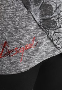 Grau, strukturiertes Stoffoberteil mit einem schwarzen Grafikdesign und dem roten "Desigual"-Logo, das auf der Vorderseite deutlich sichtbar ist.