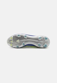 Suola di scarpa atletica viola con tacchetti di trazione argentati; presenta accenti verdi e blu, un design aerodinamico e una superficie testurizzata.