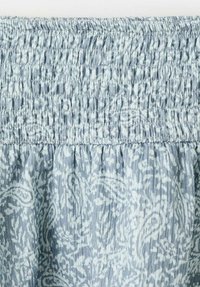 Material bleu deschis cu un model paisley și textură pliată în partea de sus. Materialul pare moale și ușor.