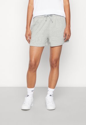 Shorts en coton gris avec une taille élastique et un cordon de serrage. Texture lisse, longueur mi-cuisse, associés à des chaussures de sport blanches et des chaussettes.