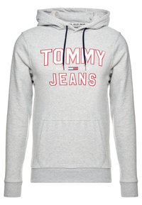 Sudadera con capucha gris con un bolsillo frontal, que presenta el texto "TOMMY JEANS" en rojo y blanco. Tiene capucha con cordón y puños y dobladillo acanalados.
