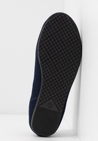 Baskets bleu marine avec une tige en tissu texturé, dotées d'une semelle en caoutchouc avec un motif de crampons pour une meilleure adhérence et durabilité.