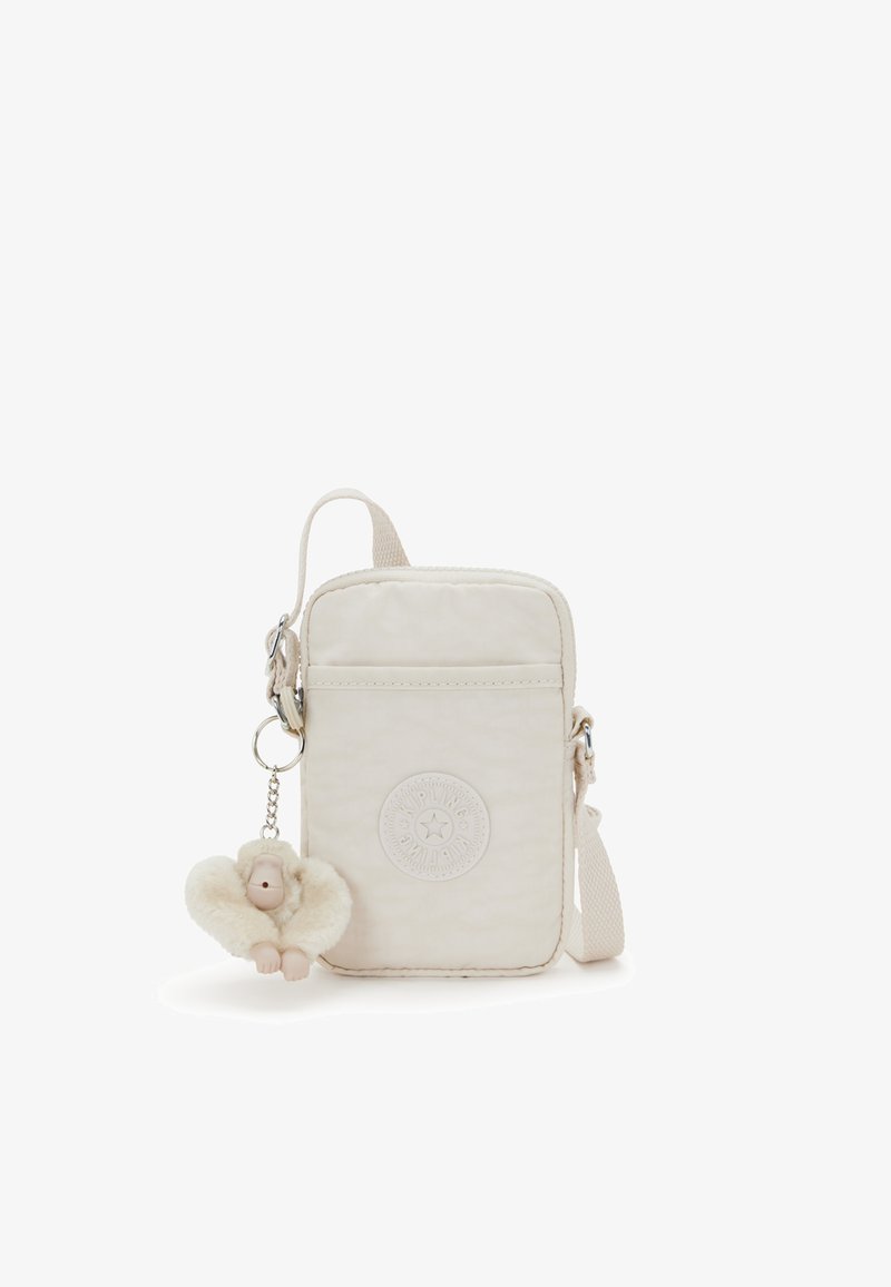 Borsa a tracolla in tessuto beige con superficie testurizzata, patch logo circolare e un portachiavi a forma di scimmia in peluche attaccato a un clip argentato.