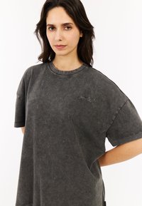 Overmaatse antracietgrijze t-shirt van zacht, textuurachtig materiaal, met een ronde halslijn en korte mouwen, voorzien van subtiele geborduurde details.