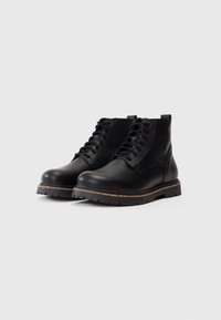Stivaletti neri in pelle con pannelli texturizzati, chiusura con lacci, suole in gomma robuste e cuciture dorate attorno al midsole per un tocco di dettaglio.