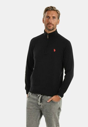 Schwarzer Reißverschluss-Pullover mit hohem Kragen, ausgestattet mit einem kleinen roten Logo auf der linken Brust sowie gerippten Bündchen und Saum.