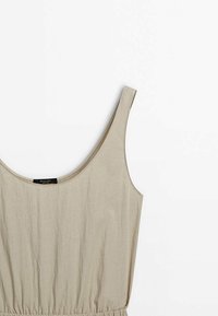 Robe beige sans manches avec un décolleté en rond, une taille élastique froncée et un tissu doux et texturé. Design minimaliste sans motifs apparents.