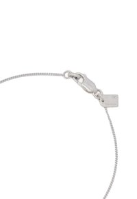 Bracelet en argent avec un design en corde torsadée et un fermoir comportant une petite étiquette. La surface est lisse et brillante.