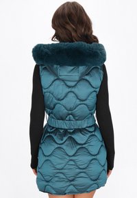 Miętowy kamizelka puchowa z kapturem z sztucznego futra, z pikowanym wzorem, z paskiem w talii i czarnymi długimi rękawami. Gładka, błyszcząca tekstura.