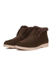 Bottines brunes avec un col en fausse fourrure douce, un matériau supérieur lisse, des détails de couture subtils et des semelles en caoutchouc de couleur claire.